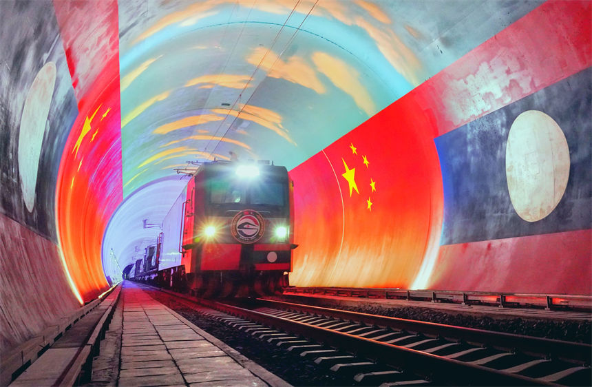在中國和老撾兩國國旗映襯下，衛(wèi)生列車即將在中老鐵路“友誼隧道”內(nèi)跨越中老兩國邊境。凱喬攝