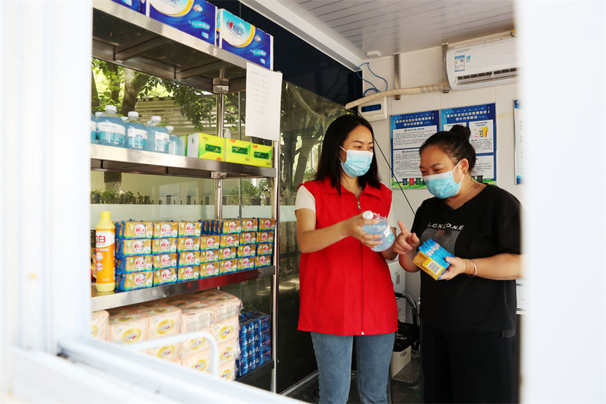 在生活垃圾分類服務驛站，管理員（左）給市民兌現(xiàn)垃圾分類積分制實物。楊敏攝