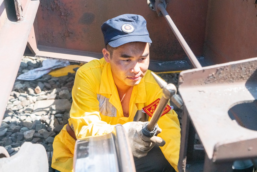 8月9日，重慶西車輛段貨車檢車員正在檢查中歐班列底部吊架技術狀態(tài)。劉彪攝