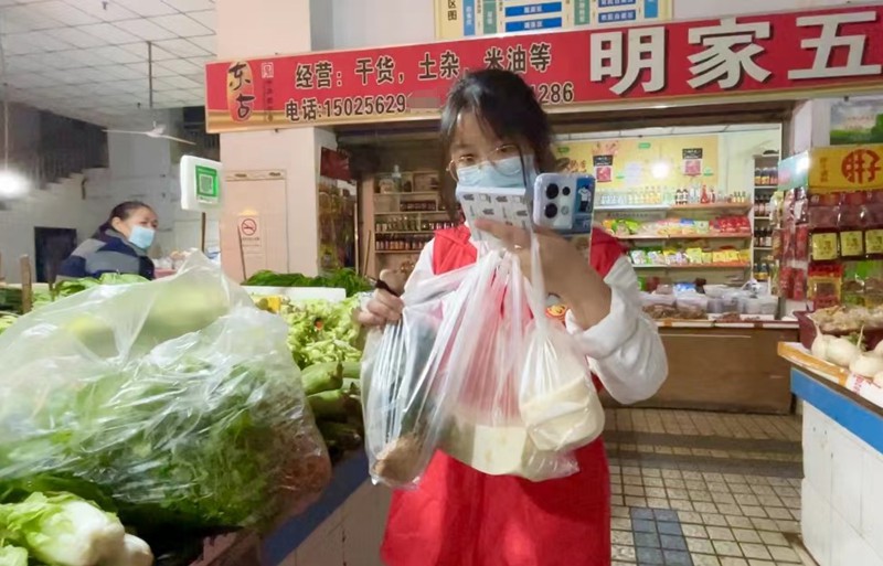 秦榕浚幫市民在菜市場(chǎng)選購(gòu)蔬菜。蔣歡攝