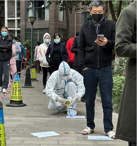 裴海民（著防護(hù)服者）在檢測點(diǎn)進(jìn)行志愿服務(wù)。