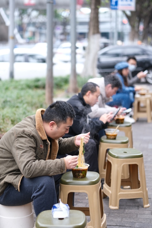 12月2日，南岸區(qū)銅元局長江村，街頭一小面館，市民在路旁吃面。郭旭攝