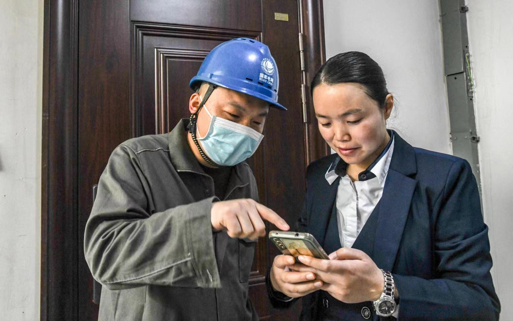 國網(wǎng)江津區(qū)供電公司員工向客戶講解二維碼的用途。王化全  攝