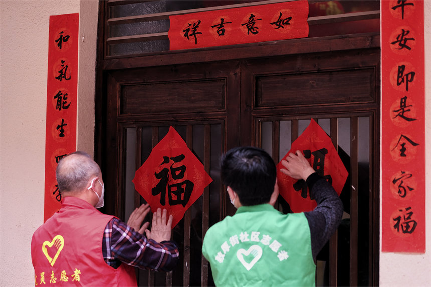 志愿者們正在為黃葛古道敦厚坡段的傳統(tǒng)民居貼春聯(lián)。郭旭攝