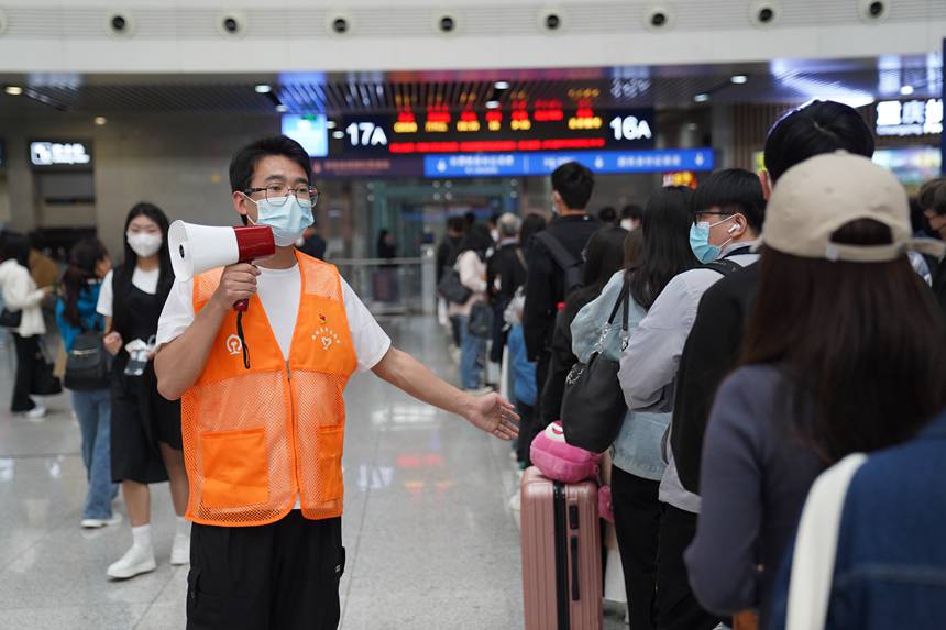 4月29日，重慶北站青年志愿者引導(dǎo)工作人員引導(dǎo)旅客排隊(duì)檢票。汪亮攝