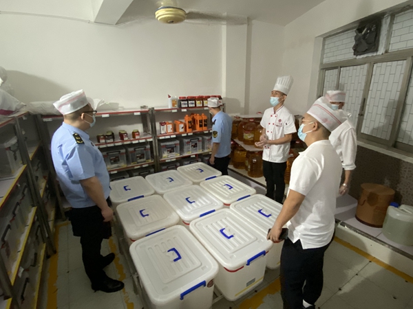 執(zhí)法人員對學校食堂食品原材料庫房進行檢查。重慶市市場監(jiān)管局供圖
