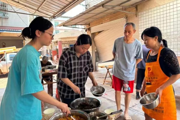 趙英潔（左二）、趙彬潔（左一）姐妹正在忙著分裝熱菜。潼南區(qū)委宣傳部供圖
