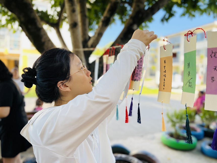 在梁平區(qū)實驗幼兒園物流園區(qū)，家長為小朋友懸掛“愛的書簽”。