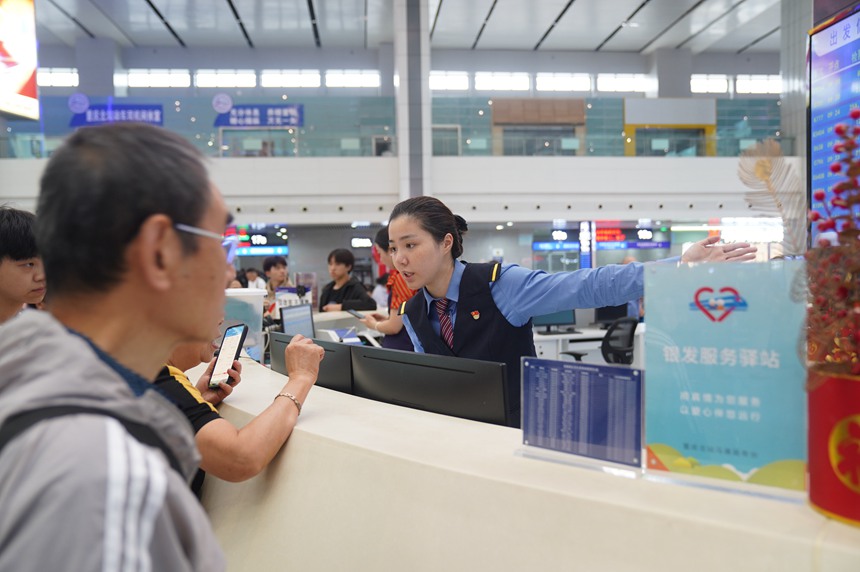 重慶北站“馬廉服務(wù)臺(tái)”工作人員引導(dǎo)旅客前往檢票口。魏偉攝