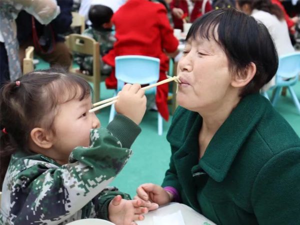 孫女正在喂奶奶吃長壽面。新絲路幼兒園供圖