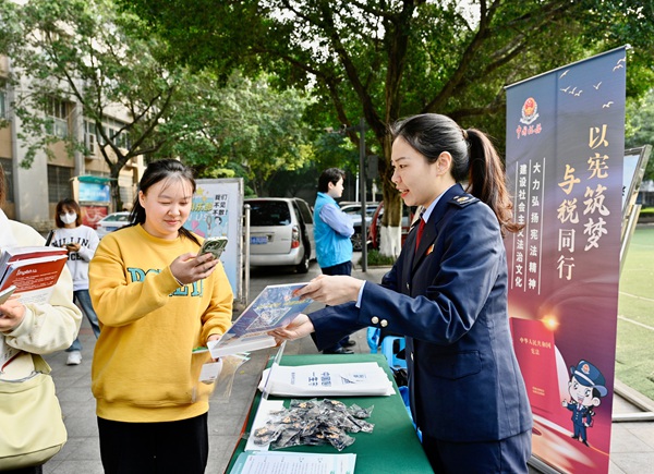 11月29日，在重慶工商大學(xué)（江北校區(qū)），江北區(qū)稅務(wù)人員引導(dǎo)學(xué)生掃碼了解憲法知識(shí)。曾鈺翀攝