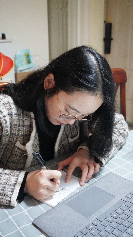 楊茜在家中寫明信片（家人拍攝）。西南大學(xué)供圖