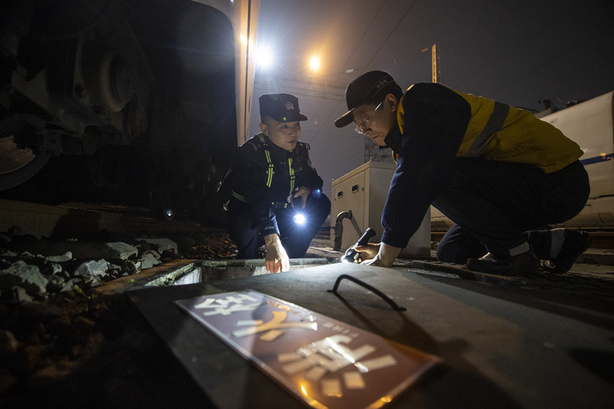 彭聰（左一）在重慶北動(dòng)車(chē)所工作人員的配合下，對(duì)存車(chē)場(chǎng)的地下式室外消火栓進(jìn)行檢查。胡勇攝