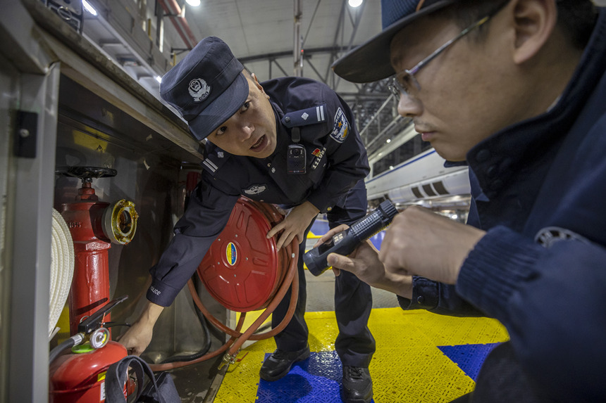 彭聰（左一）在重慶北動(dòng)車(chē)所工作人員的配合下，對(duì)檢修庫(kù)的消防栓進(jìn)行檢查。胡勇攝