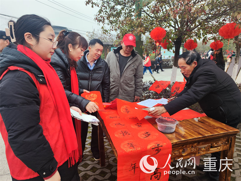 當(dāng)?shù)氐臅◥酆谜攥F(xiàn)場(chǎng)書寫對(duì)聯(lián)為鄉(xiāng)親們送上新春祝福。人民網(wǎng) 陳琦攝