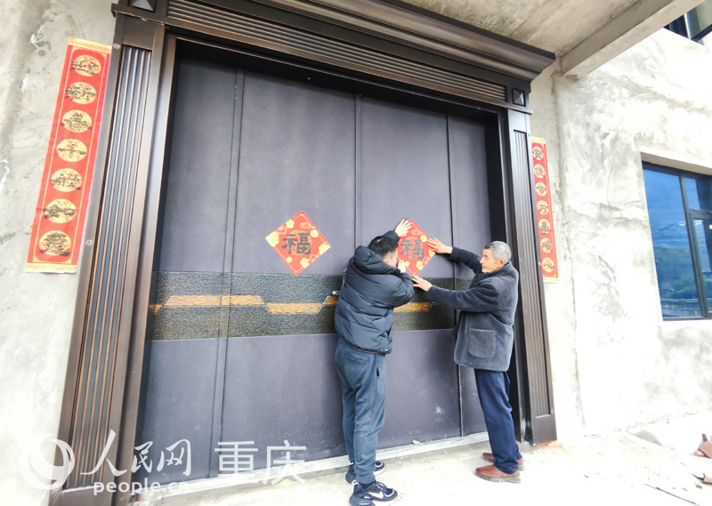 村干部幫佘中華新家張貼福字和春聯(lián)。人民網 陳琦攝
