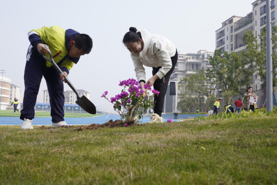 圖為學(xué)生與家長代表共同植樹現(xiàn)場。秦廷富 攝