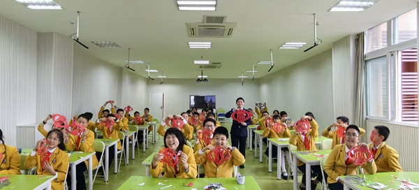 在大足區(qū)迪濤學校，稅務(wù)人員和同學們與“稅徽”剪紙合影留念。孟祥菲攝