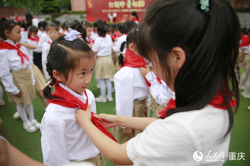 高年級學生為新入隊的少先隊員佩戴紅領(lǐng)巾。人民網(wǎng)記者 劉政寧攝