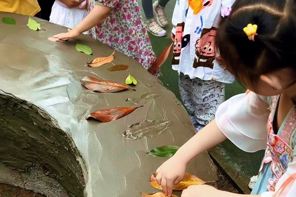 孩子們創(chuàng)作樹葉拓印水泥桌現(xiàn)場。二師附二幼供圖