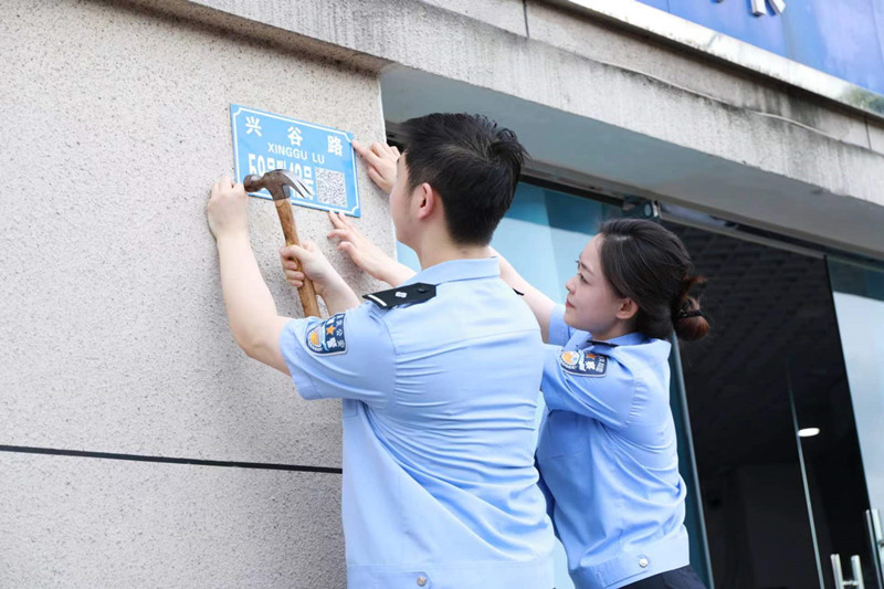 民警在興谷路裝訂二維碼門樓牌。重慶高新區(qū)公安分局供圖
