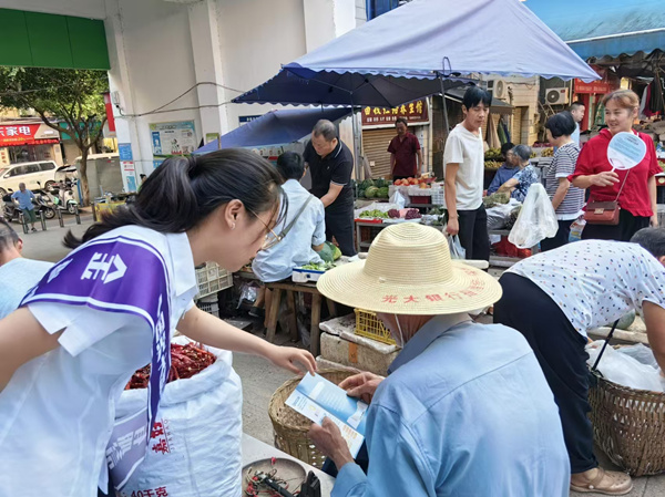 志愿者走訪農(nóng)村集市的各個攤位，進行流動宣傳。光大銀行重慶分行供圖