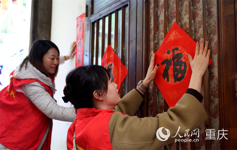 志愿者們?yōu)辄S葛古道敦厚坡老街掛燈籠。人民網(wǎng)記者 劉祎攝
