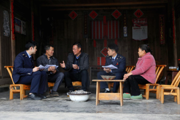 秀山縣稅務(wù)局派駐云隘村的第一書(shū)記陳夕才（左三），與一同前往的稅務(wù)工作人員挨家挨戶走訪，為云隘村村民詳細(xì)講解醫(yī)保等相關(guān)政策。張?chǎng)┗輸z
