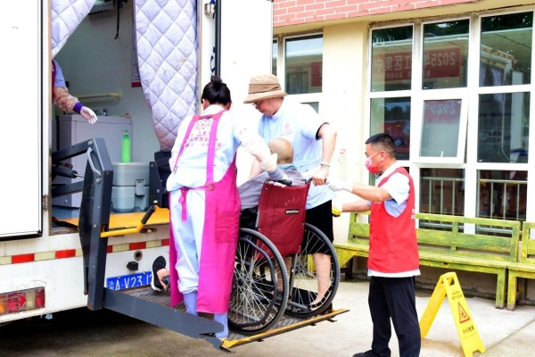志愿者扶老人進入助浴車。楊晨攝